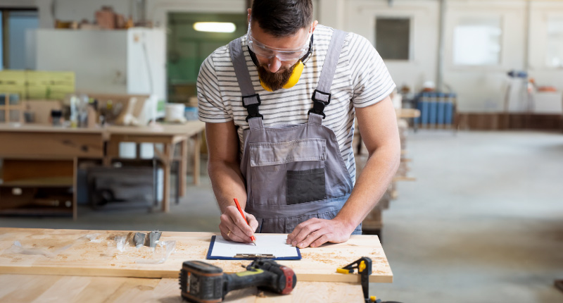 Handwerker zeichnet präzise auf einem Werkstatttisch